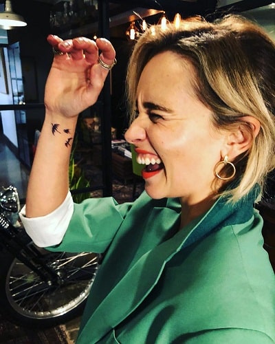 A picture of Emilia Clarke showing her dragons' tattoo.